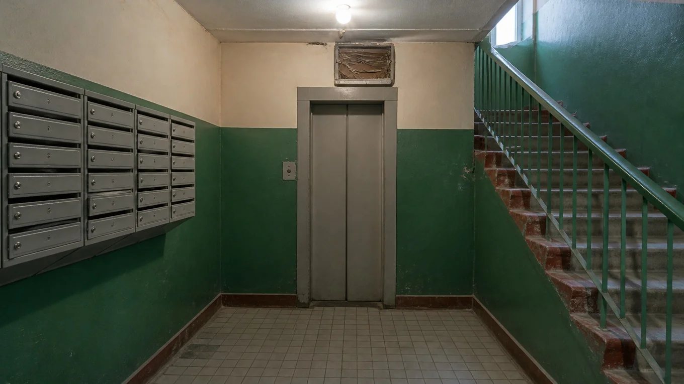 Обычный подъезд жилого дома: узкий тамбур, почтовые ящики на стене, лестница за перегородкой
